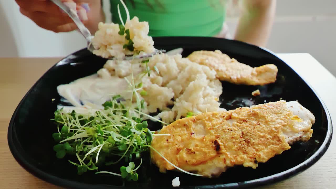 Slow motion of woman enjoying healthy meal with chicken, rice, and greens