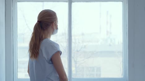 woman looking out a window during isolation