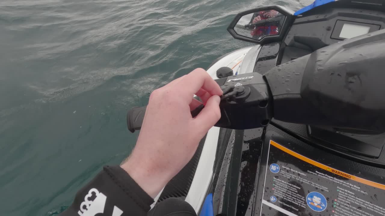 Ripresa POV di un pilota di moto d'acqua che mostra come togliere e inserire l'interruttore di sicurezza.
