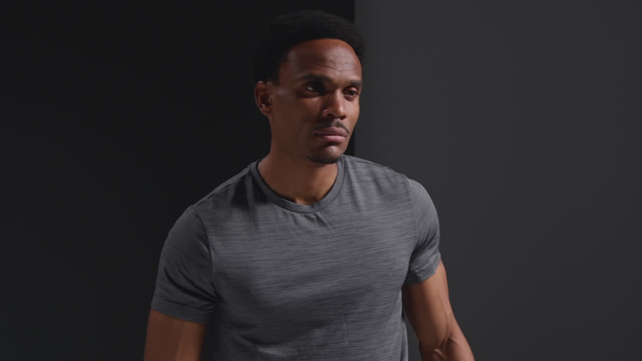 Studio Portrait Of Male Boxer Training Or Exercise In Gym Folding Arms Against Black Background