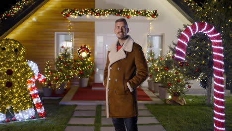 Man in front of a house decorated for Christmas