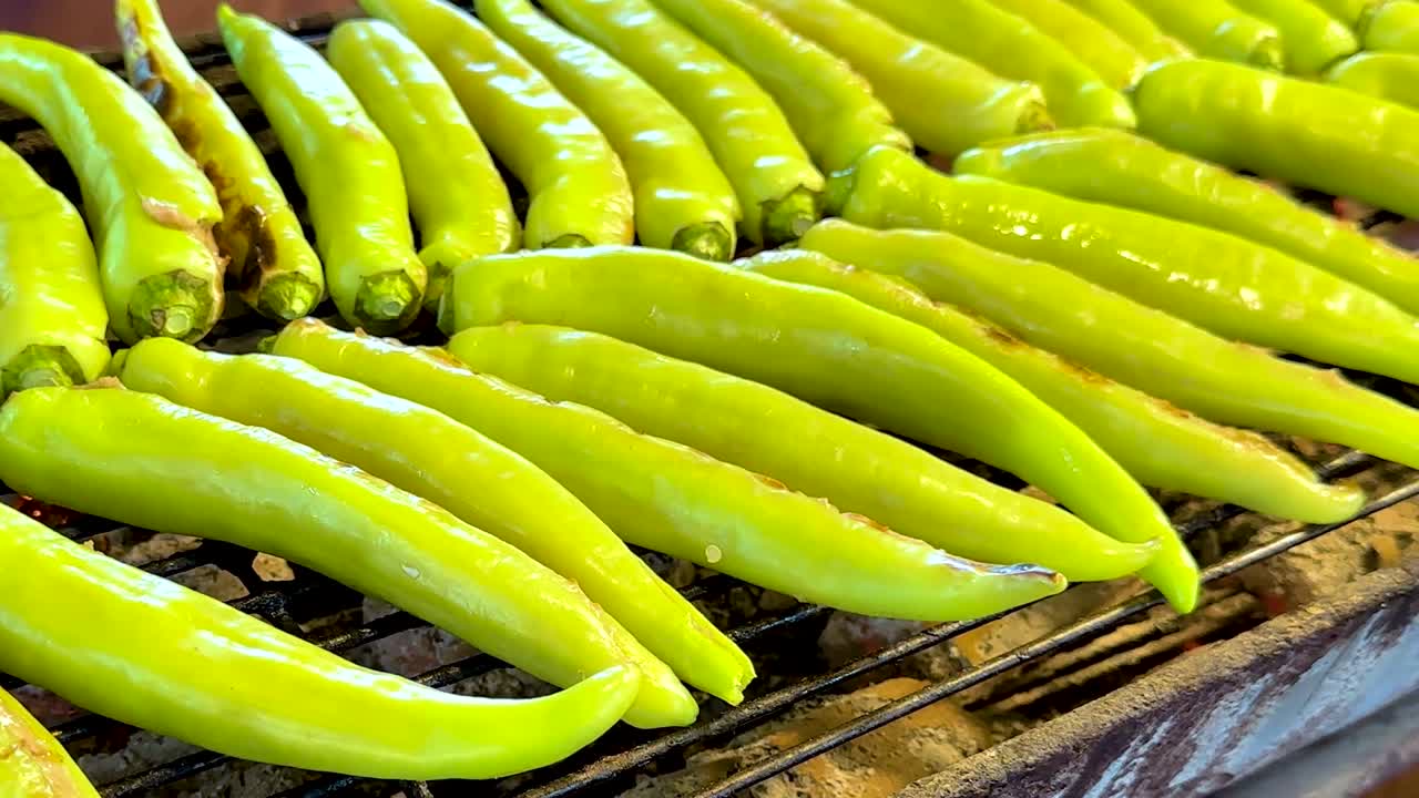 A close-up view of vibrant green peppers neatly arranged on a grill rack.