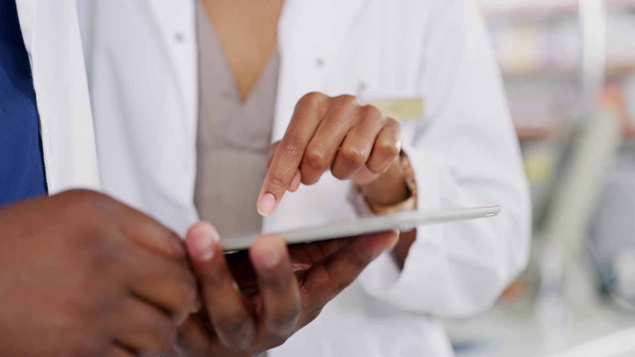 two unrecognizable pharmacists looking at a tablet