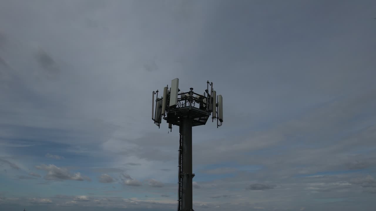 5G cellular base station tower showing multiple sector panel antennas, remote radio units, mounting brackets, and cabling, illustrating modern mobile network infrastructure, slow motion shot