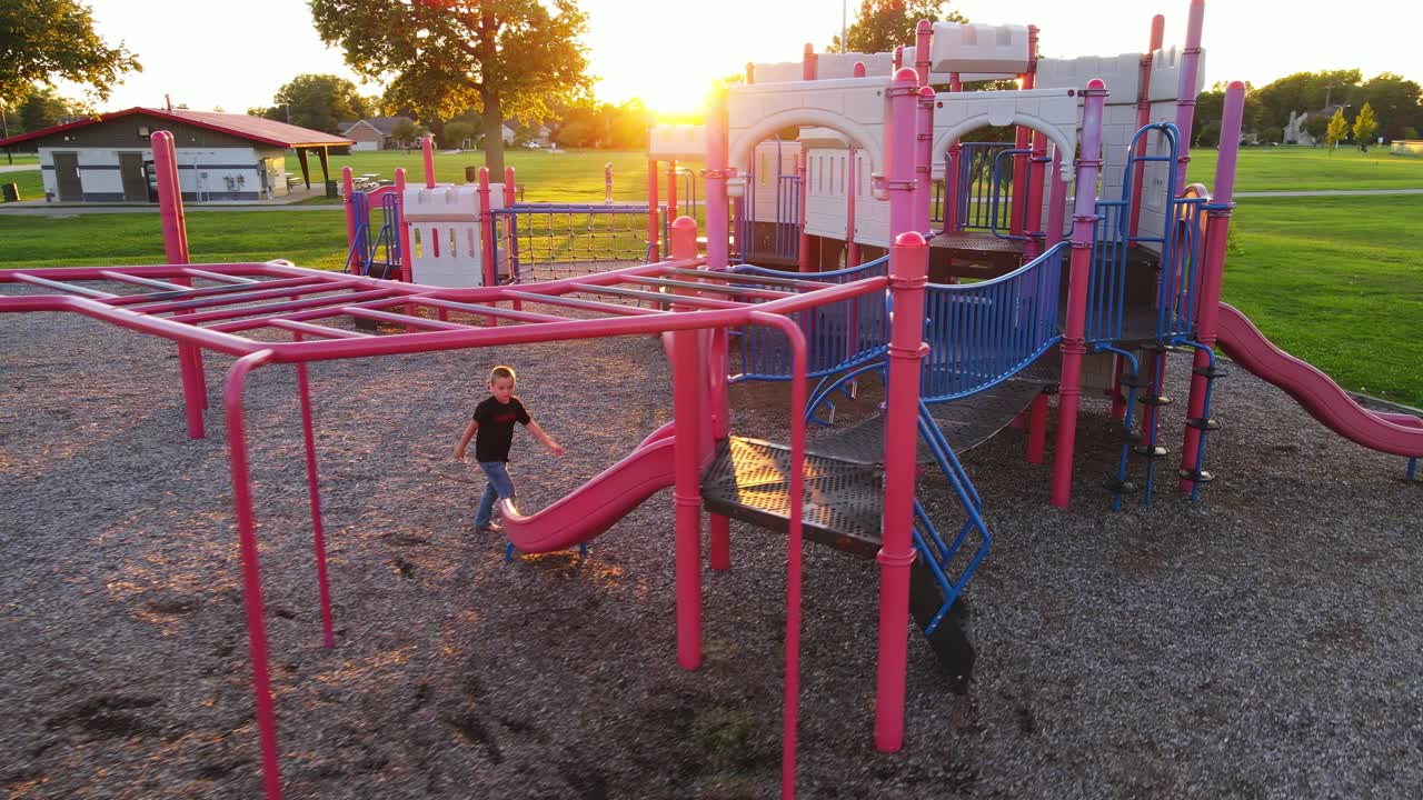 Young boy enjoys playground on sunny evening, aerial view