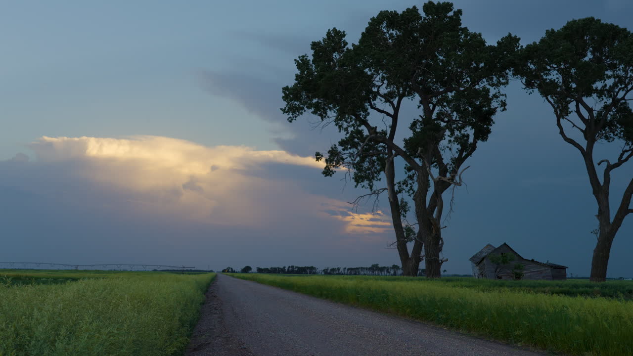 A quiet dirt road and a colorful stormy evening sky