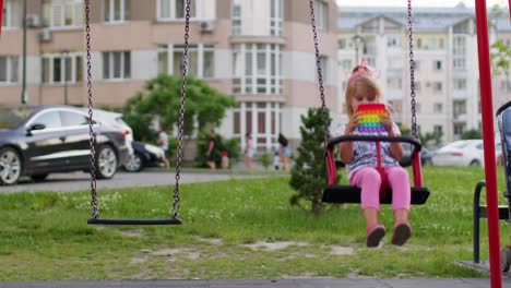 Un-Niño-Pequeño-Y-Elegante-Juega-Con-Un-Moderno-Juego-De-Juguetes-Sensoriales-Blandos-Con-Burbujas-Pop-It-En-Un-Columpio-En-El-Patio-De-Recreo