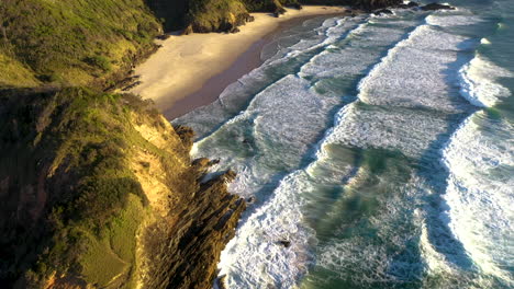 epic drone shot starting on crashing waves then revealing coastline at broken head coast near byron bay