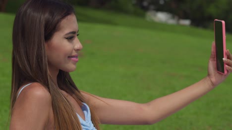 young hispanic woman taking a selfie while enjoying a picnic on a golf course