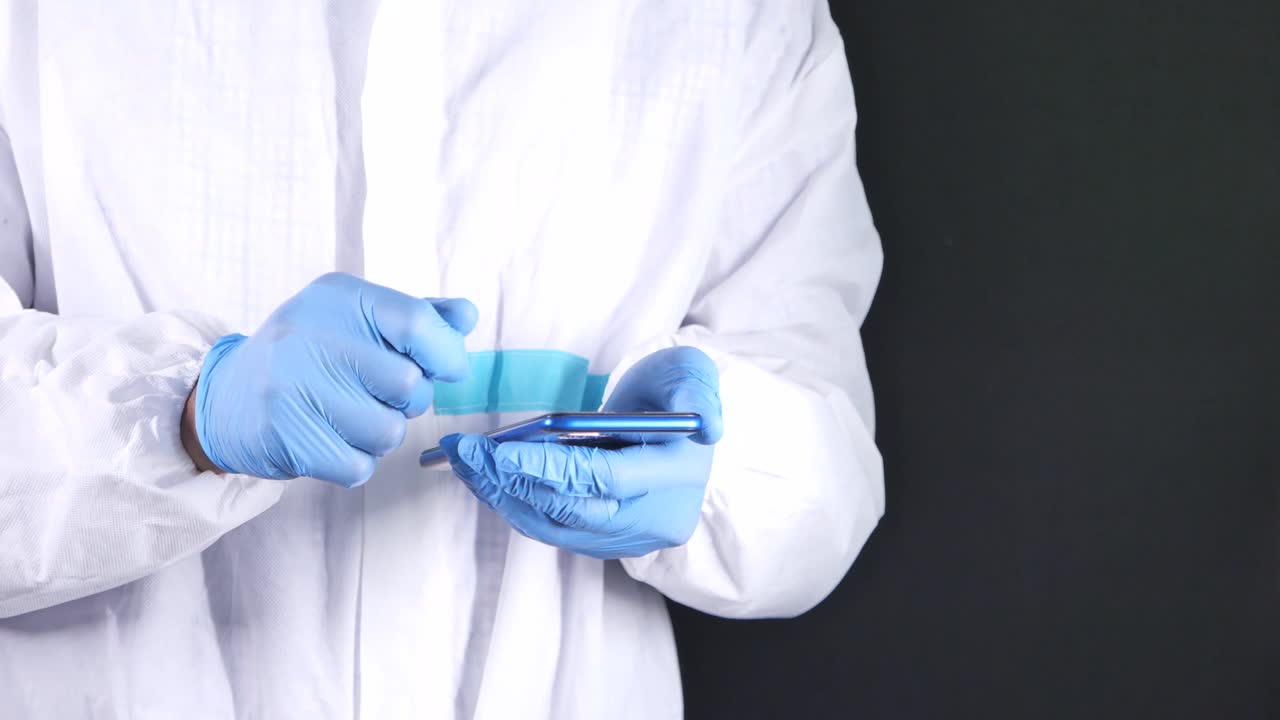 trabajador médico que utiliza un teléfono inteligente con traje de protección