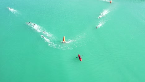 Aerial-hover-above-beautiful-turquoise-water-as-triathlon-swimmers-round-buoys---Oamaru-Harbor