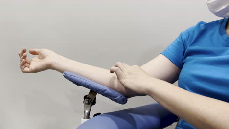 close capture of a woman pressing a cotton ball on her arm after drawing blood for testing