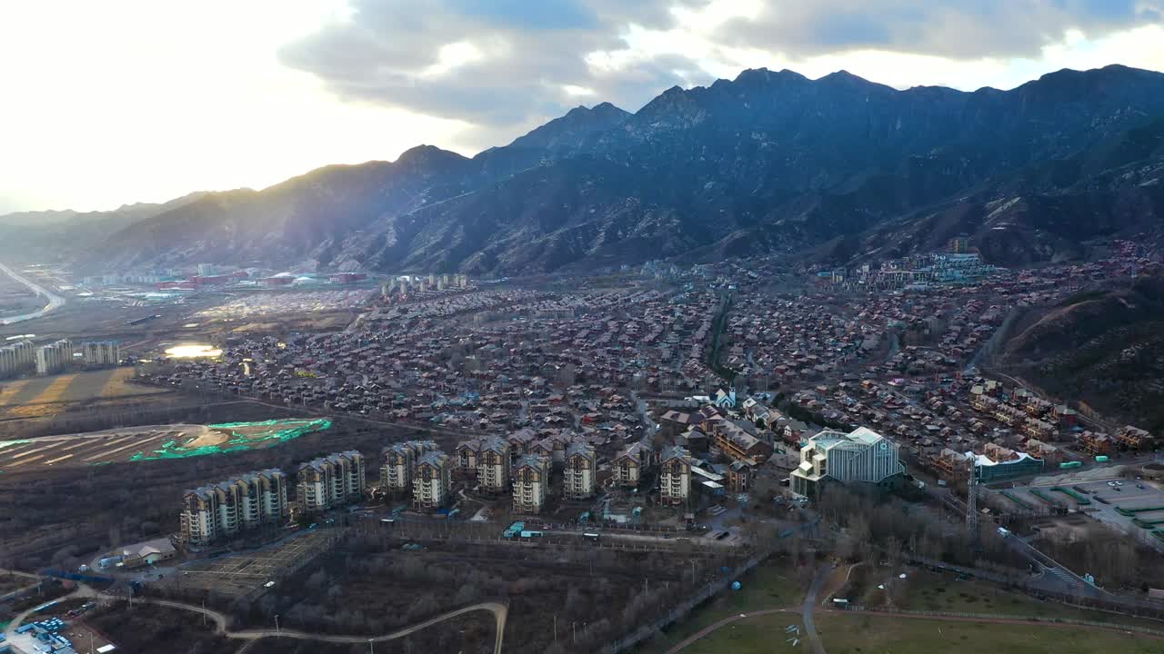 Super wide drone shot of Jackson Hole, near Beijing, China. A Chinese fake copy town inspired by the American town Jackson in Wyoming, USA. Vast landscape with city view, mountains in the background.