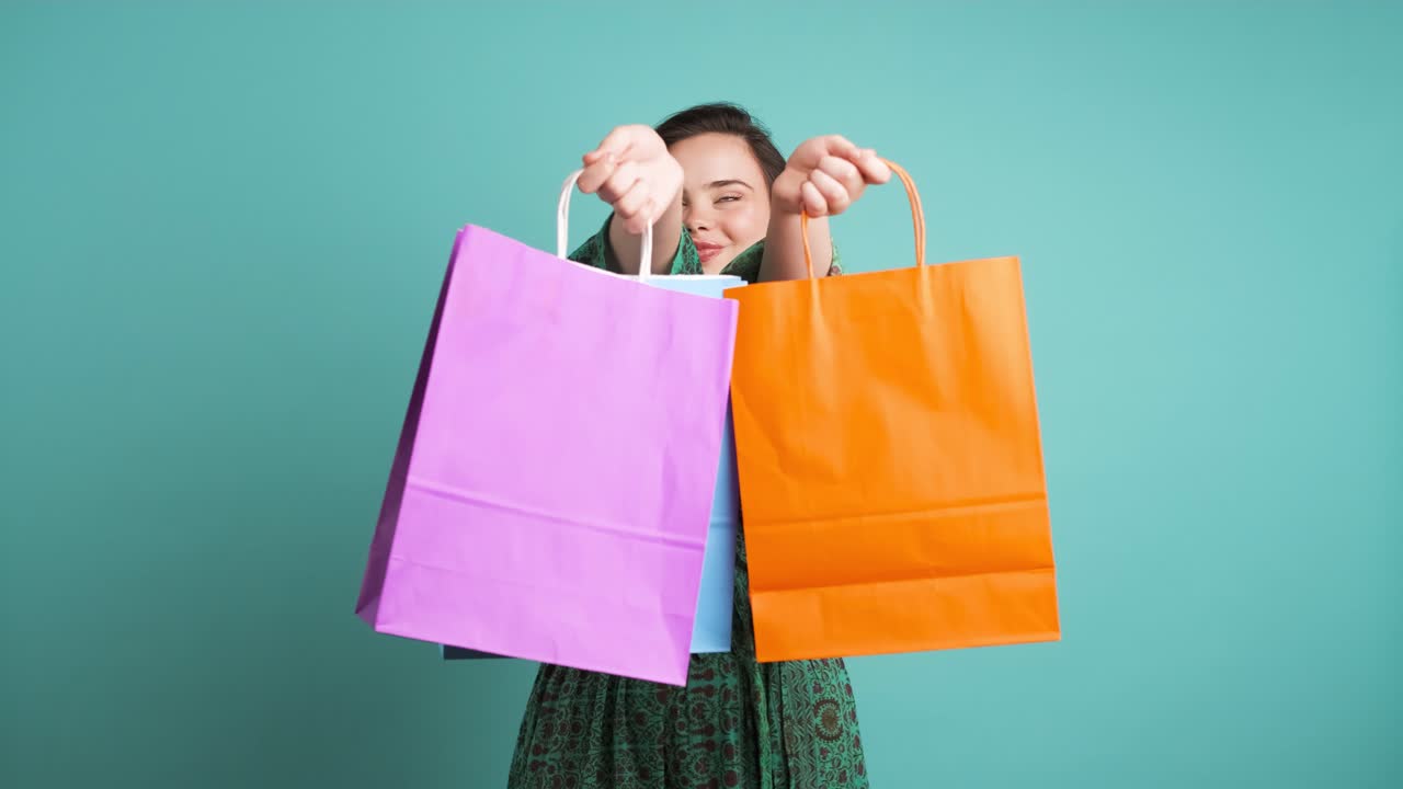 Happy woman showing shopping bags in blue studio