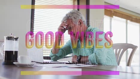 animation of good vibes in pink over happy caucasian senior man using laptop in kitchen