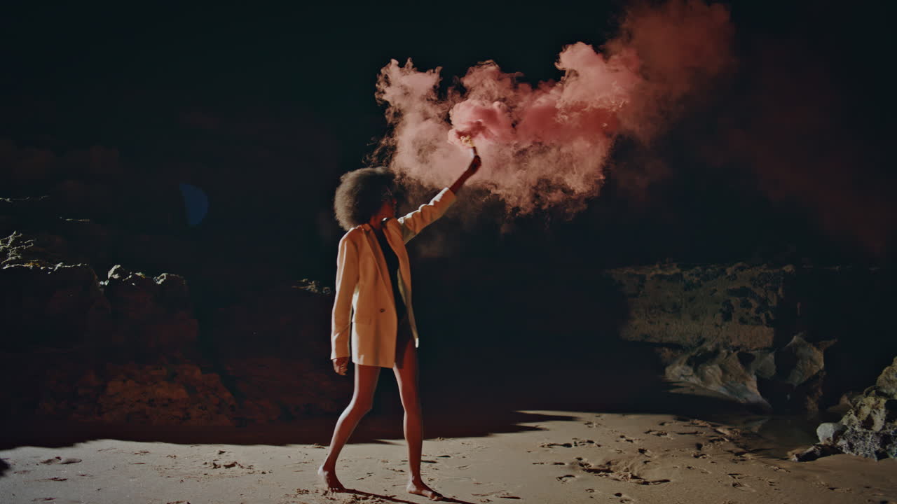 Fashion woman waving bomb on night beach. Protest girl holding smoke grenade