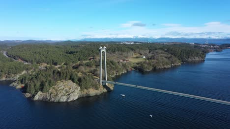 stord bridge triangle connection on stord island in norway - bridge with traffic in beautiful sunny day - aerial flying over sea and looking towards island of stord