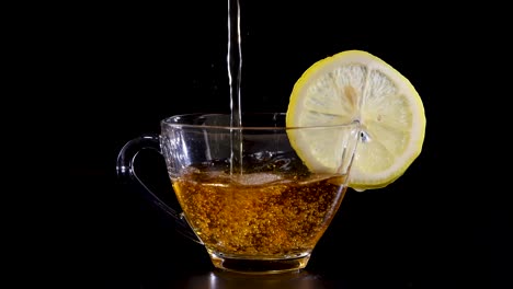 glass cup with lemon slice filled with tea against a black backdrop. captures dynamic liquid motion and vibrant colors