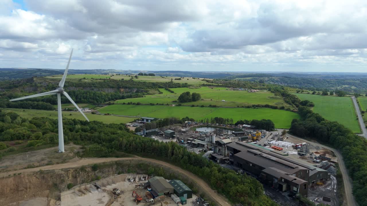 Drone aerial perspective of renewable energy windmills with industrial aggregates and green hills in Derbyshire Dales United Kingdom