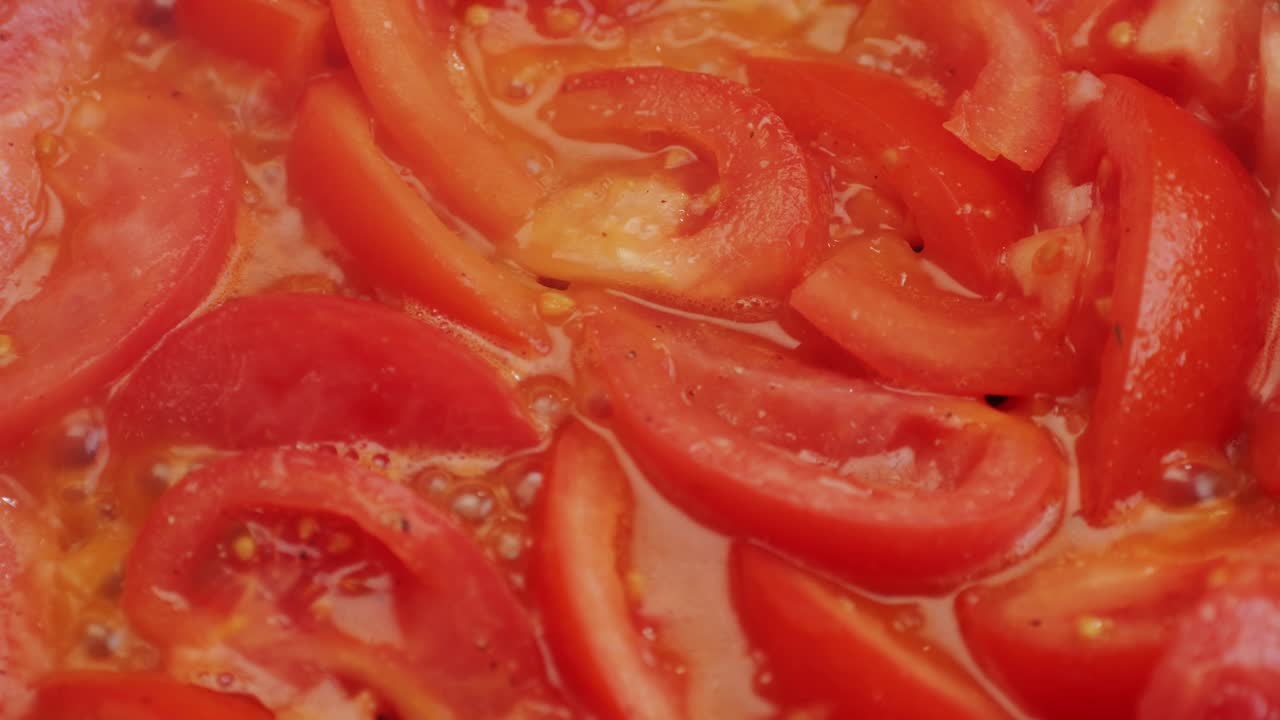 Cooking fresh peeled sliced tomato Juice sauce in pan, peeled tomatoes boiling in their own juice, making tomatoes pasta sauce .Top view close up, Italian traditional cuisine food.
