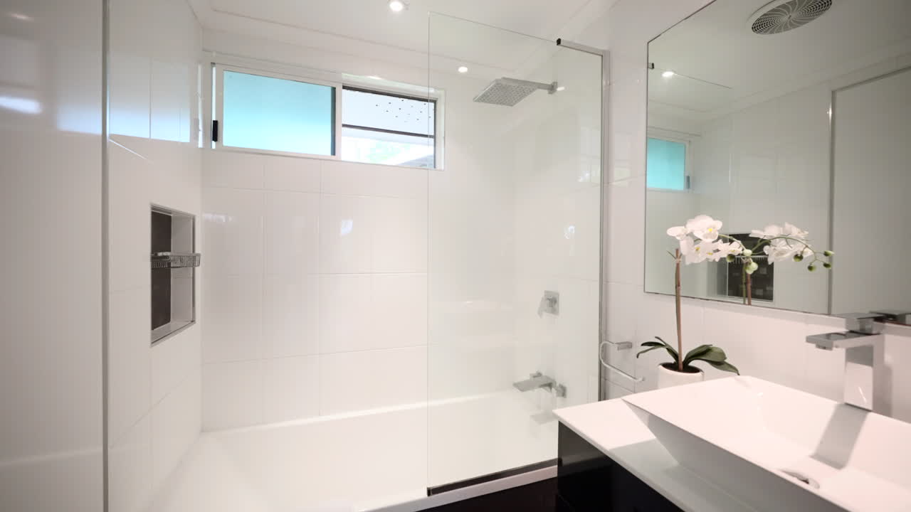 Push in to crisp black and white contemporary modern bathroom with large mirror, shower tub, and wash basin