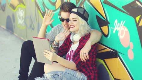 Fun-young-couple-waving-at-a-tablet-pc