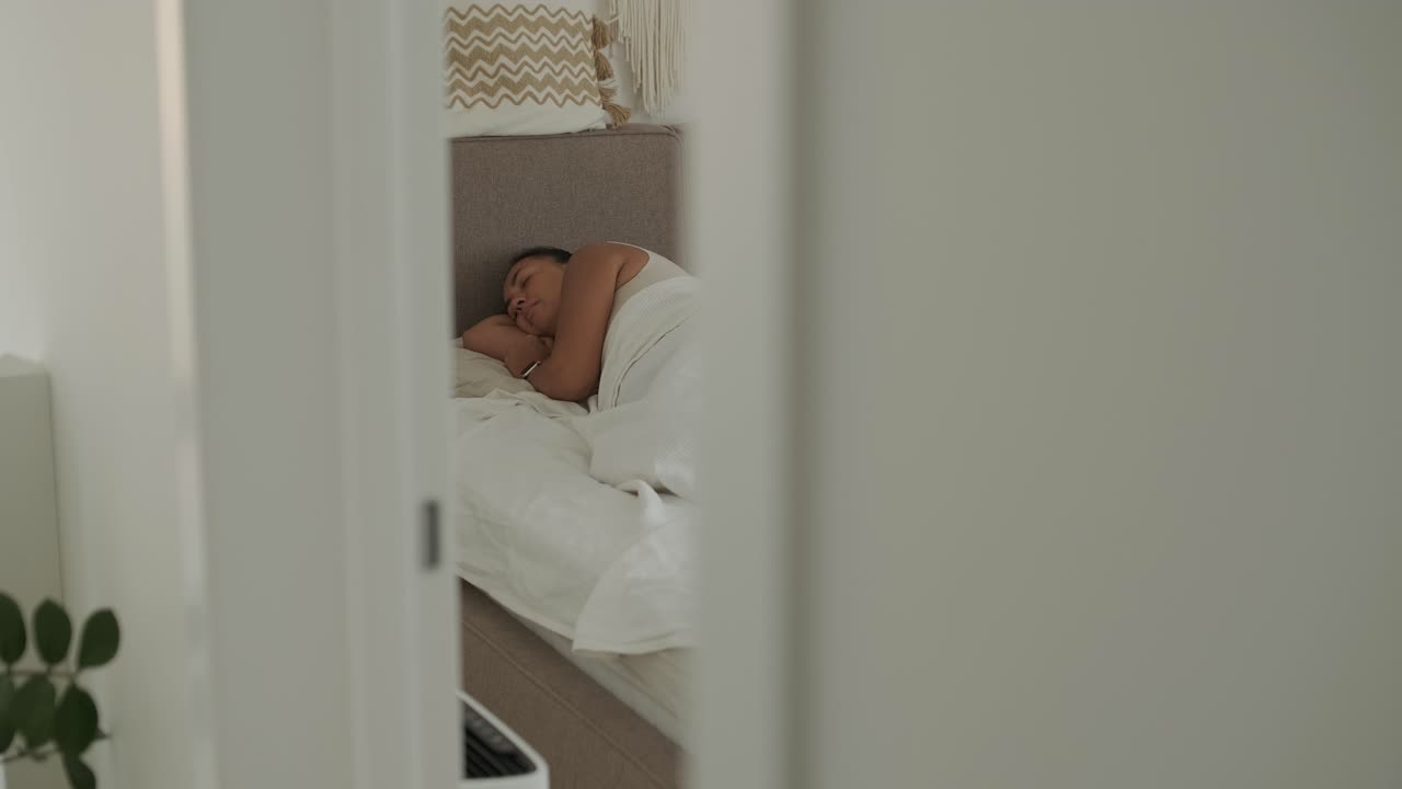 Una scena serena di una donna incinta sdraiata su un letto, che accarezza il suo pancione, in una luce naturale soffusa. L'atmosfera trasmette comfort e attesa materna
