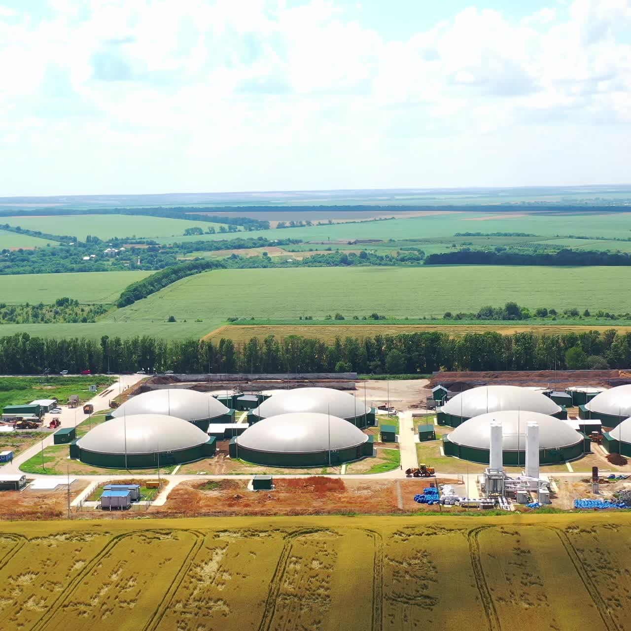 Modern farm for biogas production on field. Innovative factory among beautiful nature. Special round reservoirs for methane-containing gas