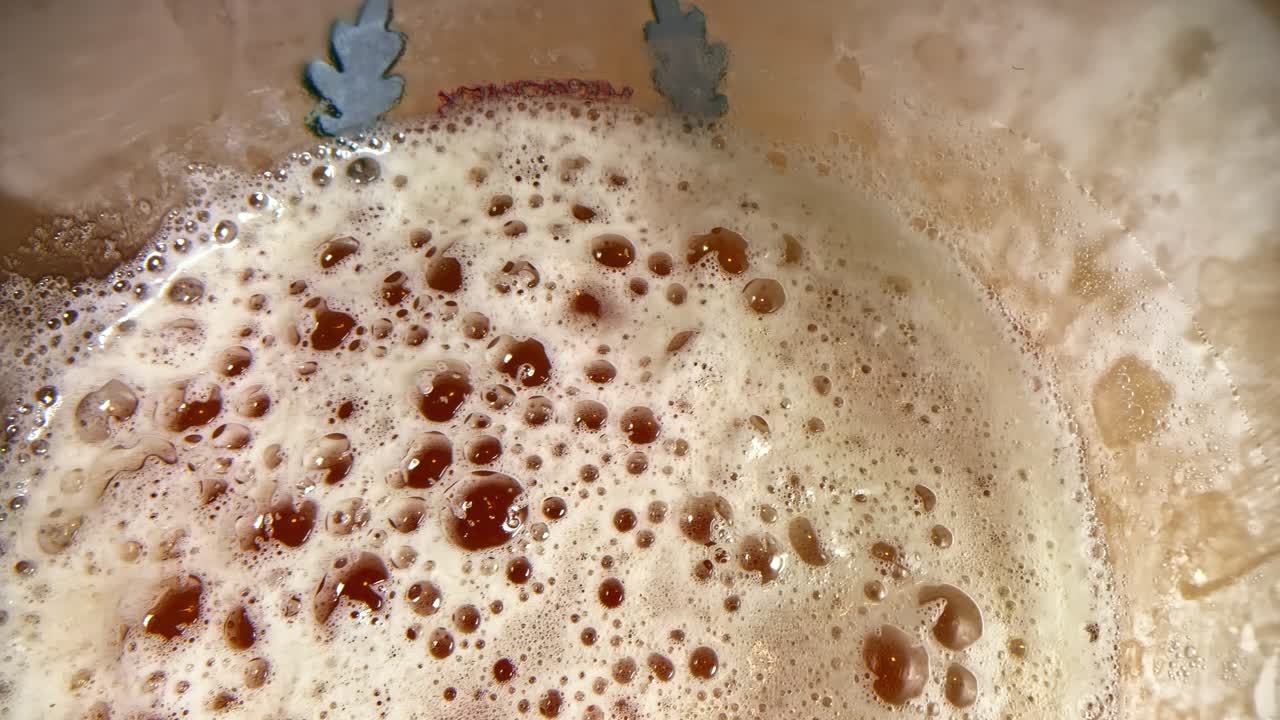 Håndværksøl med skum, mørkebrun farve, alkoholisk drik med bobler helt tæt på