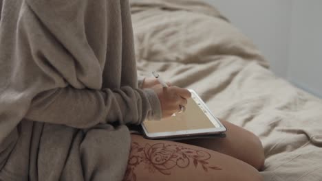 woman drawing on tablet in bed