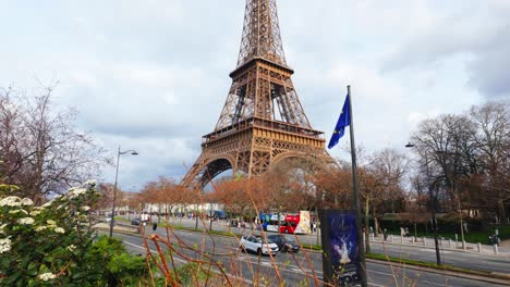 los coches están circulando debajo de la torre eiffel por la tarde.