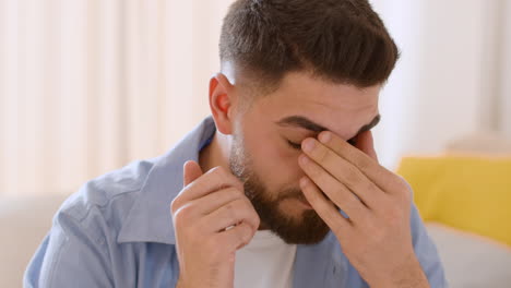 man rubbing his tired or painful eyes/face