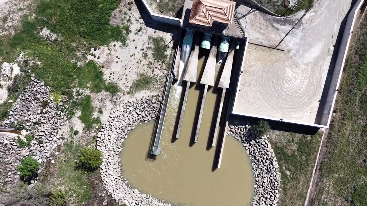 Uma tomada de drone de cima para baixo acompanhando o fluxo de água saindo da estrutura de descarga da usina hidrelétrica de Barbate.