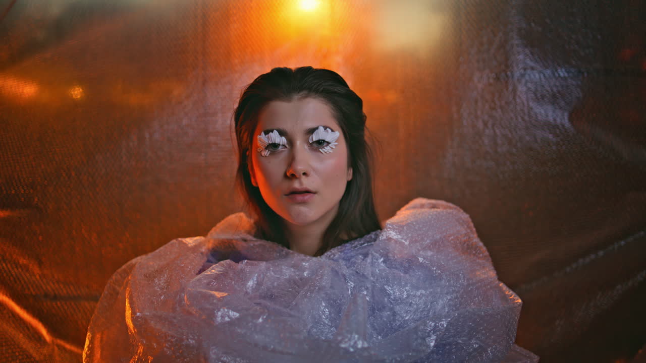 близкий кадр девушки, обернутой в пузырьковую оболочку, отражающую уникальный стиль. женщина с лепестковыми ресницами