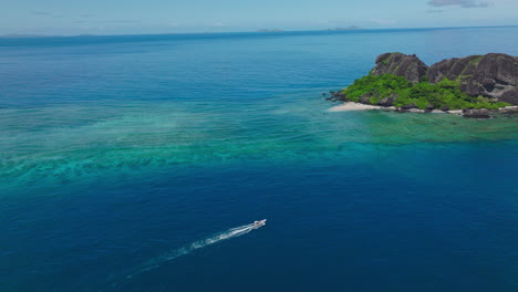 tropical tour boat gliding over open turquoise ocean in midday sun toward remote island
