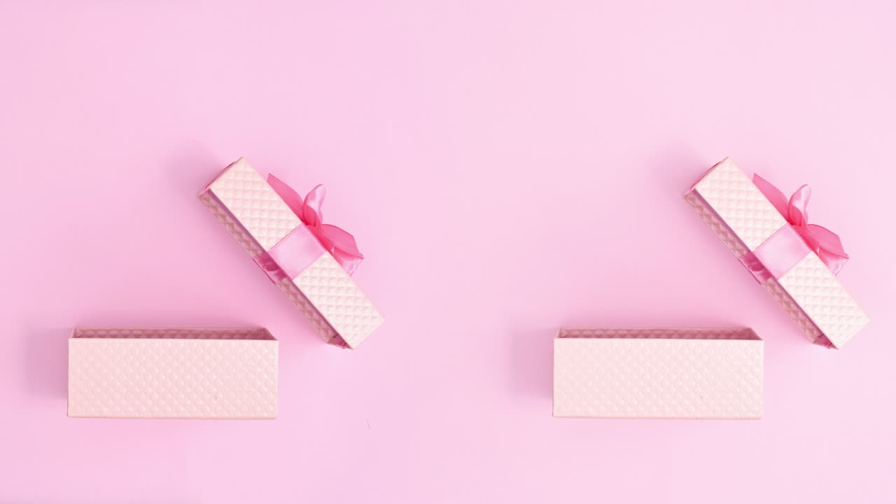 Two double pastel pink gifts open and heart balloons comes out. Stop motion flat lay