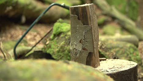 Zeitlupe-Nahaufnahme-Einer-Axt---Beilschneiden---Zertrümmern-Eines-Holzscheites---Holzknüppel-Mit-Einer-Säge-Im-Hintergrund