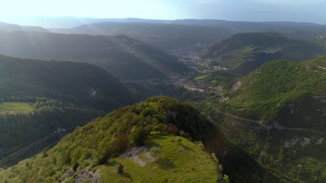 vista aérea de las verdes montañas jura francesas con bengalas solares y la ciudad de saint-claude en el fondo del valle