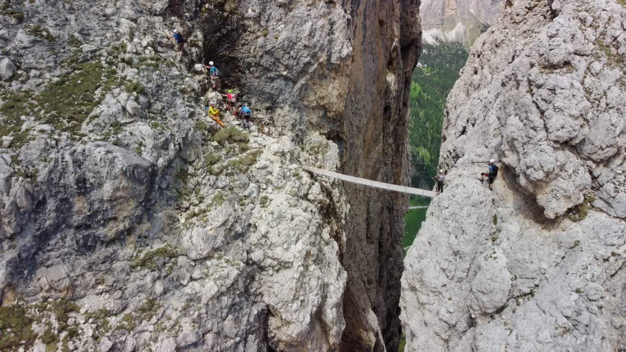 Climbers navigating the challenging Pisciadù Via Ferrata, crossing a narrow suspension bridge, Dolomites, Italy