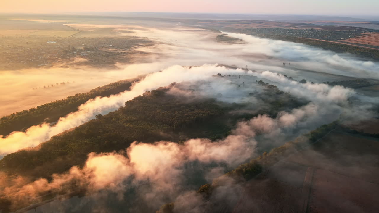 Aerial drone view of nature of Moldova at sunset. River and lush fog above it, village, greenery