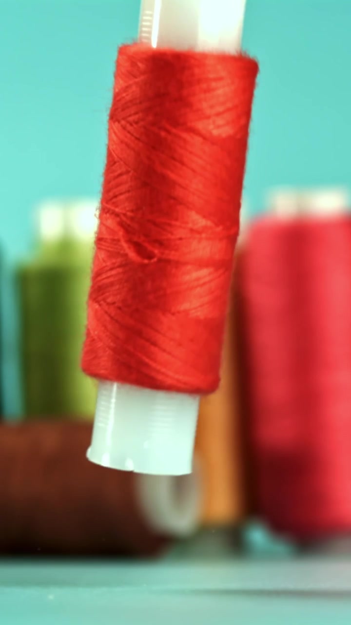 Red Thread Spool Falling in Slow Motion with Colorful Background