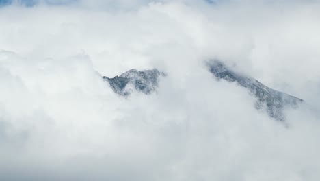 lapso de tiempo de la empinada cima de la montaña rodeada de nubes grises en el cielo
