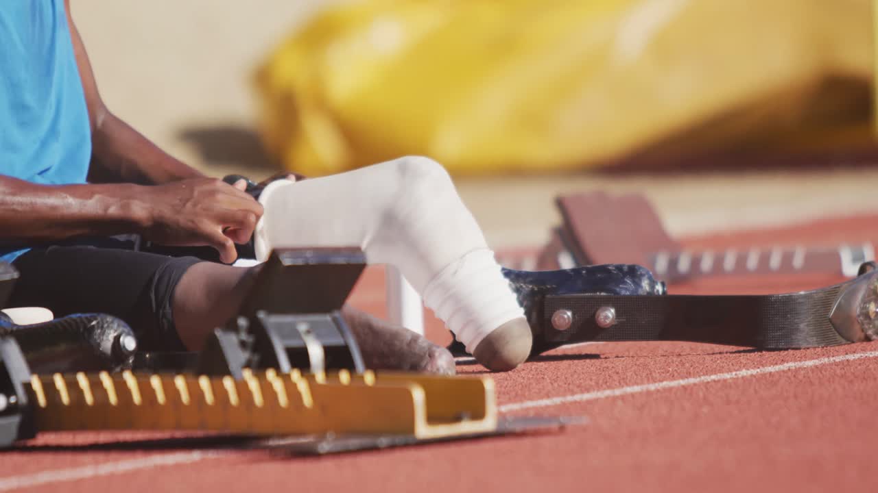 Disabled mixed race man with prosthetic legs sitting and putting his bandage on