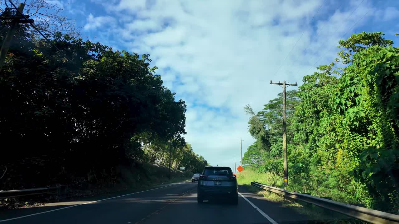 Driving through a lush tropical landscape with road signs