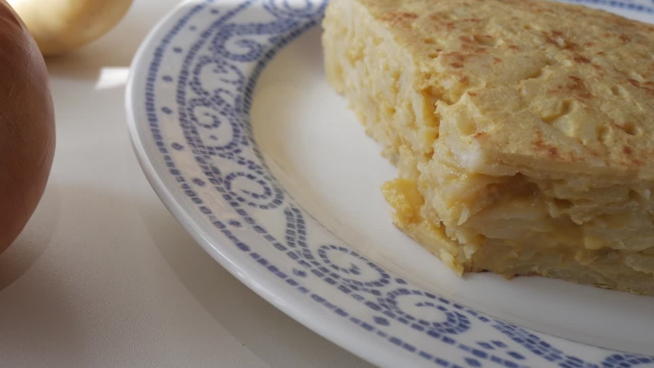 A slice of Spanish Potato Omelette Tortilla on a white plate, soft and golden