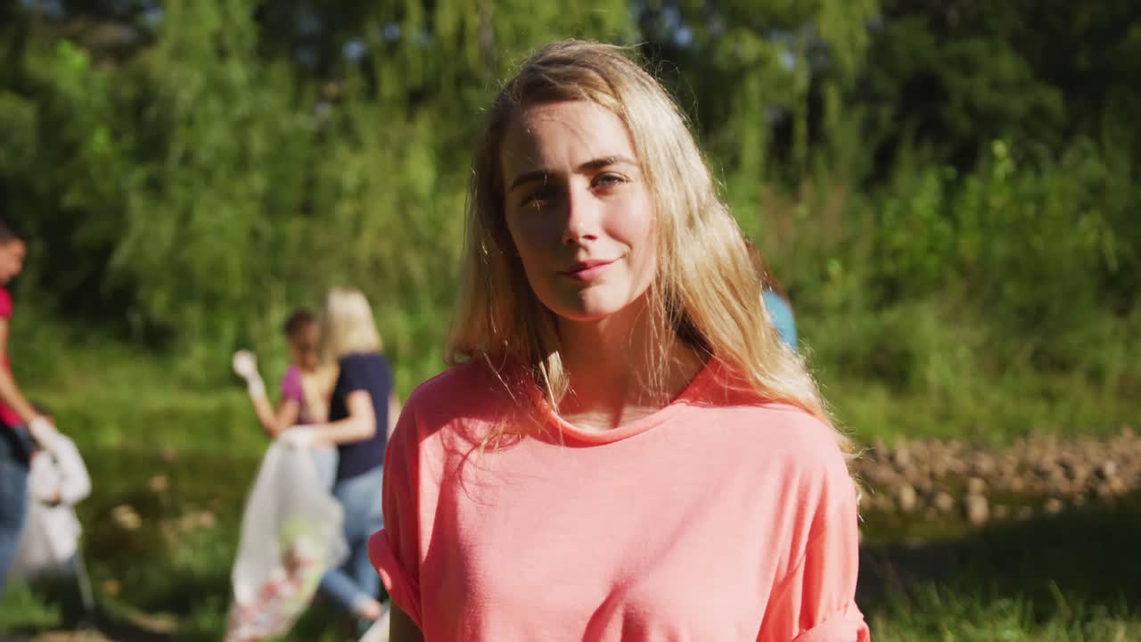 кавказская женщина улыбается и смотрит в камеру во время очистки реки