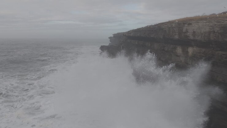 Puissantes vagues océaniques se brisant contre une falaise côtière escarpée