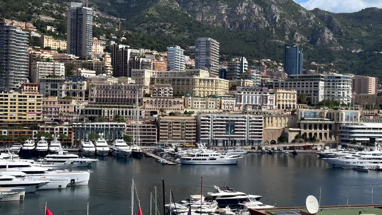 Modern solar panels on roof of building at marina port of Monaco Town. Sunny day in french city state. Yachts and sailing boats parking in front of hilly housing area. Towers and downtown in summer.