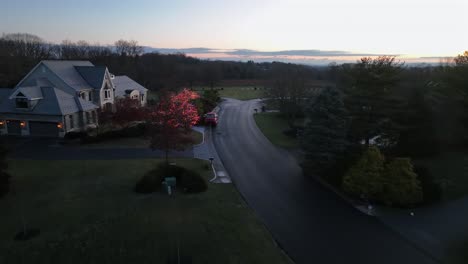 upper class suburb neighborhood in american town during sunrise. large villa buildings and mansion in with christmas decoration in rural area. aerial birds eye flyover shot.