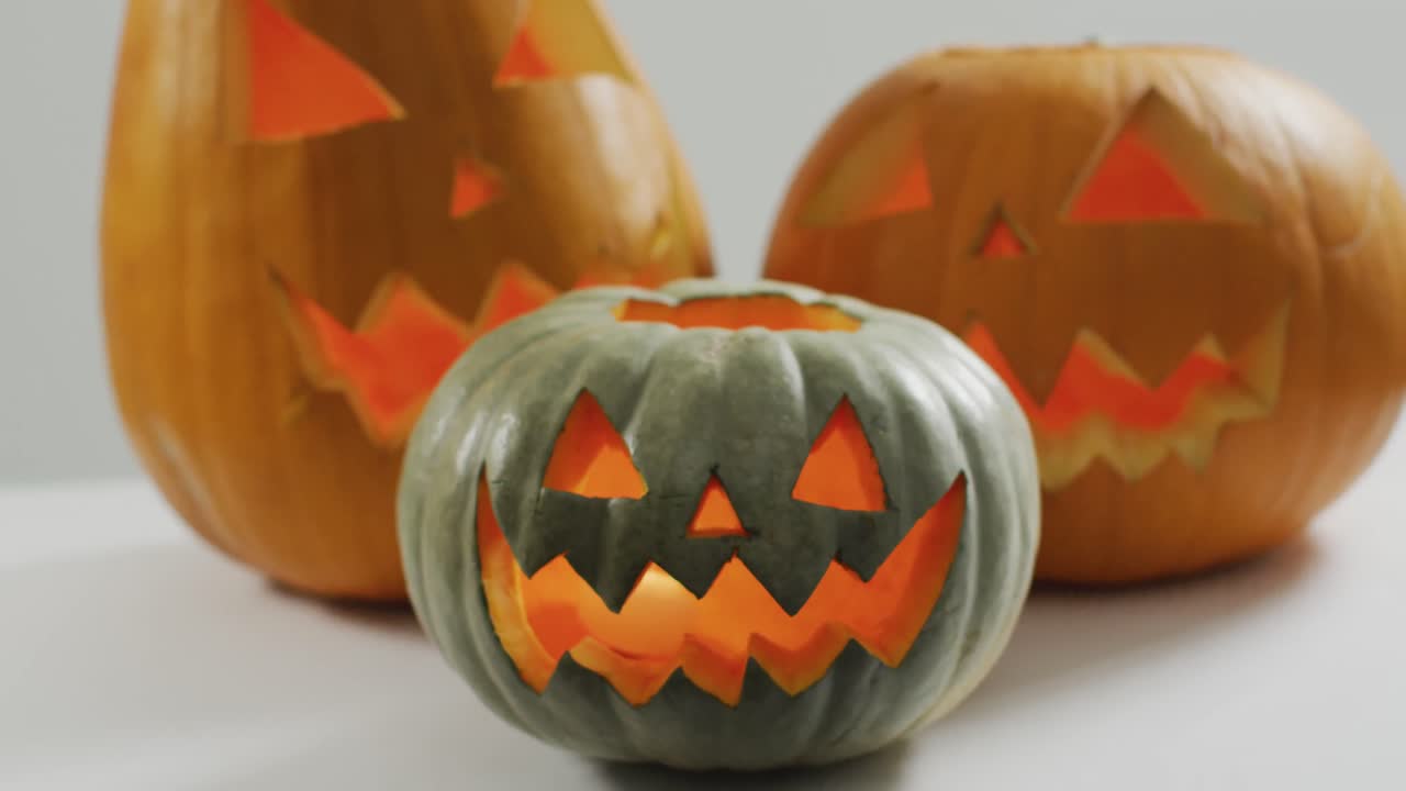 vista de cerca de varias caras aterradoras talladas calabaza de halloween contra un fondo gris